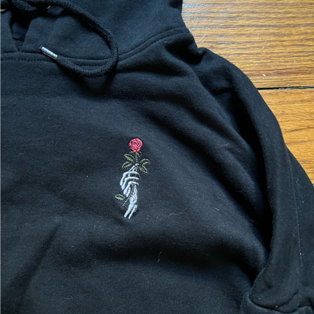 Black skeleton hand hoodie with rose details on sleeves.